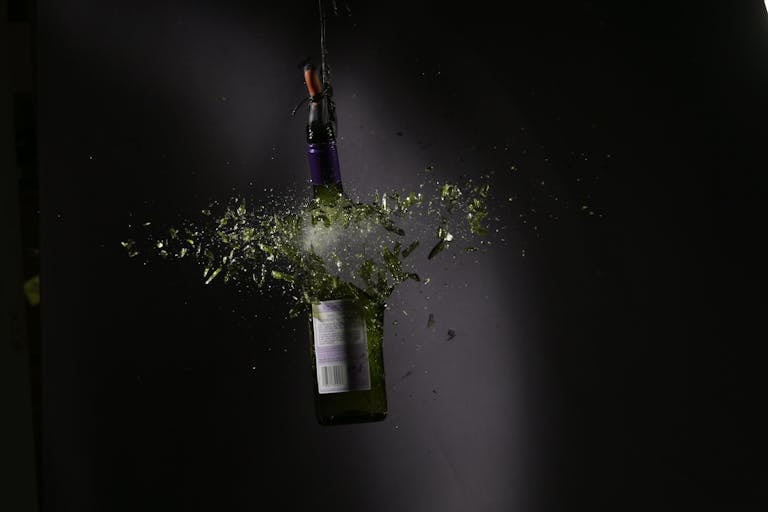 High-speed capture of a glass bottle shattering with vibrant shards.