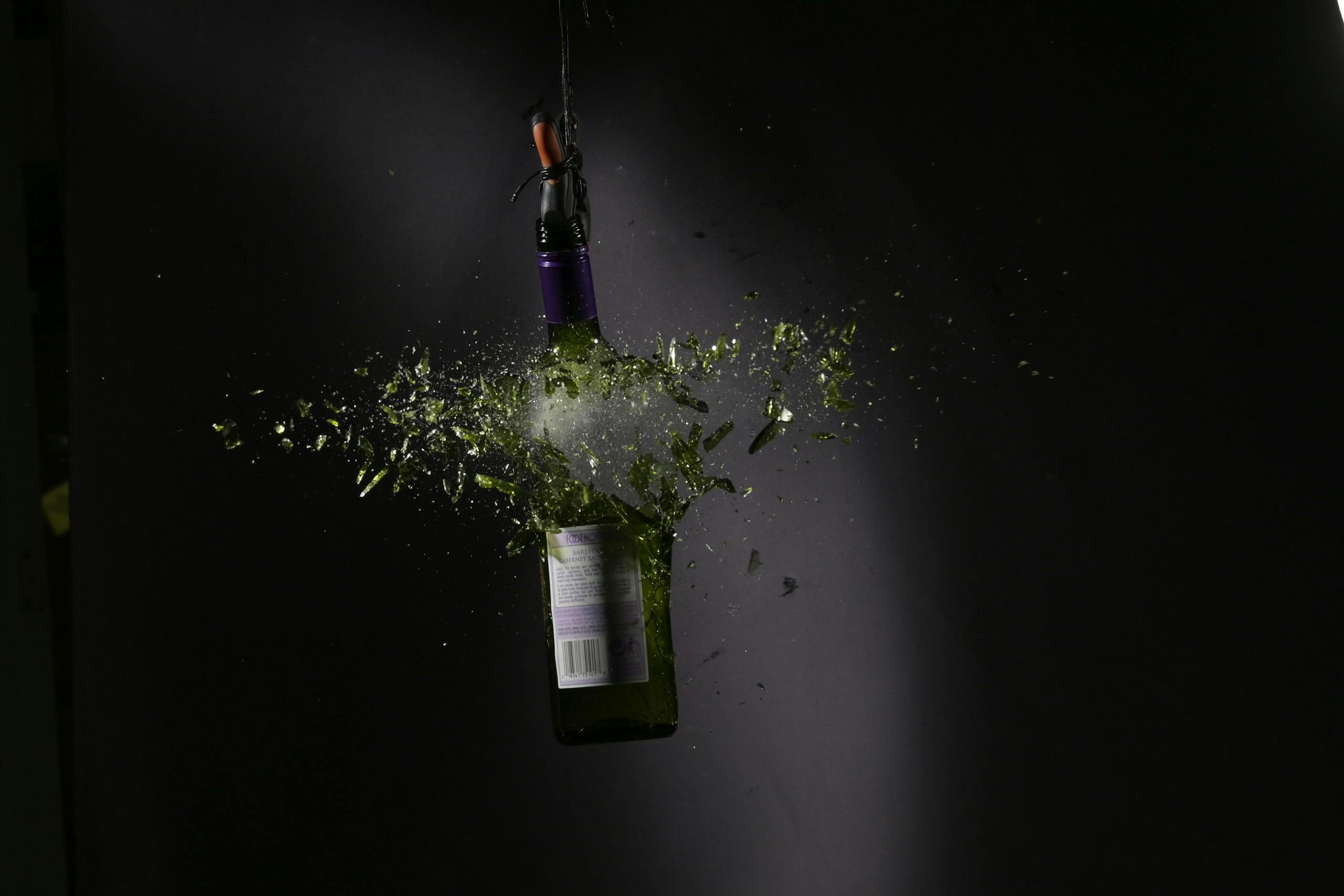 High-speed capture of a glass bottle shattering with vibrant shards.